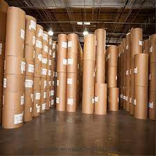 A technician inspecting a roll of kraft paper for quality assurance